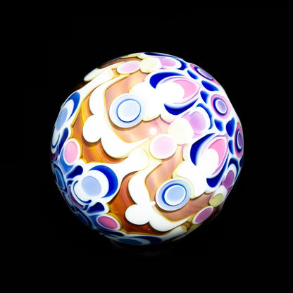 Colorful glass marble with intricate abstract patterns in pink, blue, and white on black background