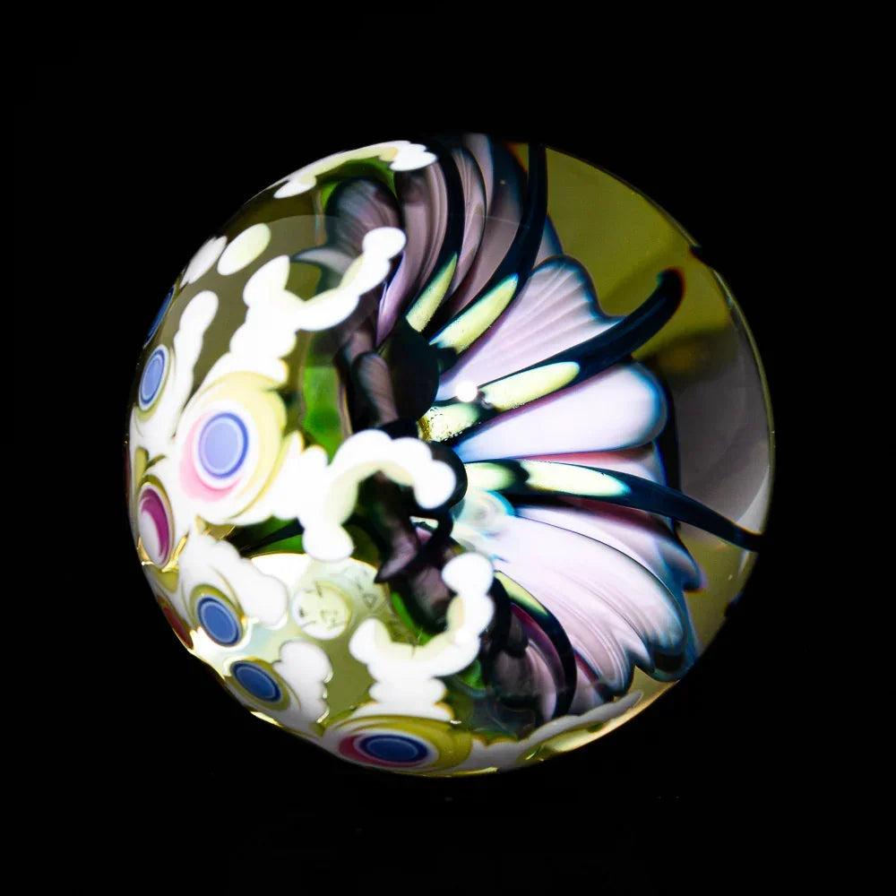 Heady glass marble with intricate flower and colorful pattern against black background