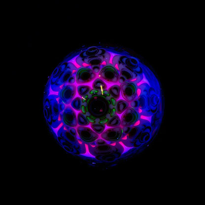 Colorful UV-reactive glass art piece with intricate patterns and neon details on black background