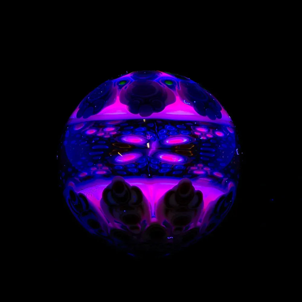 Colorful UV-reactive glass orb with intricate purple and blue patterns on black background