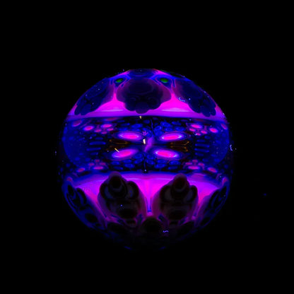 Colorful UV-reactive glass orb with intricate purple and blue patterns on black background