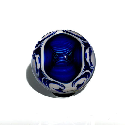 Deep blue glass marble with white swirled patterns, heady glass art on white background