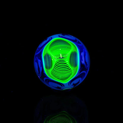 Glowing green and blue glass marble with intricate spiral pattern on black background