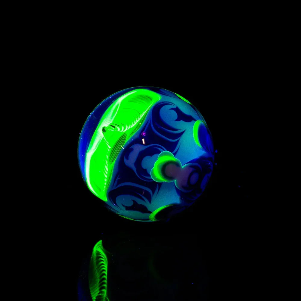 Glowing blue and green heady glass marble with intricate patterns on black background