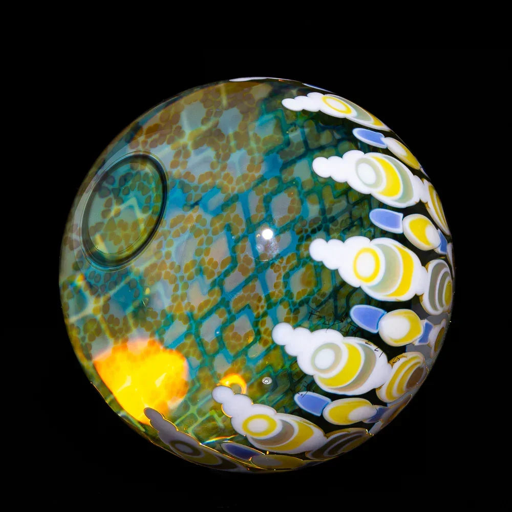 Art glass orb with intricate blue, yellow, and white patterns on a black background