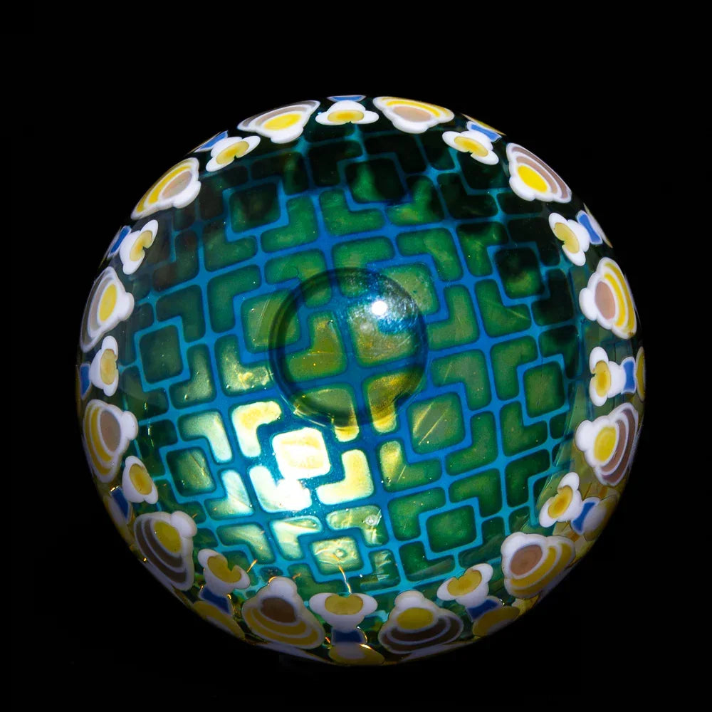 Handcrafted glass orb with geometric teal pattern and yellow floral accents, black background