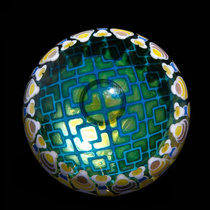 Handcrafted glass orb with geometric teal pattern and yellow floral accents, black background