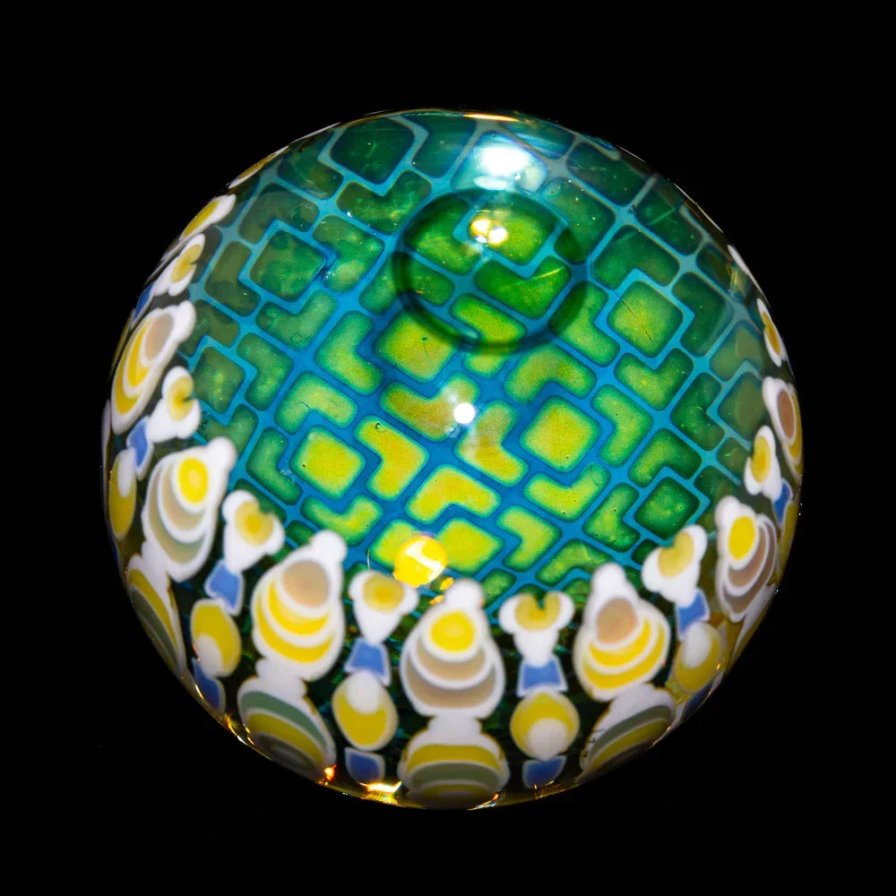 Colorful glass marble with geometric green pattern and yellow-white accents, on black background