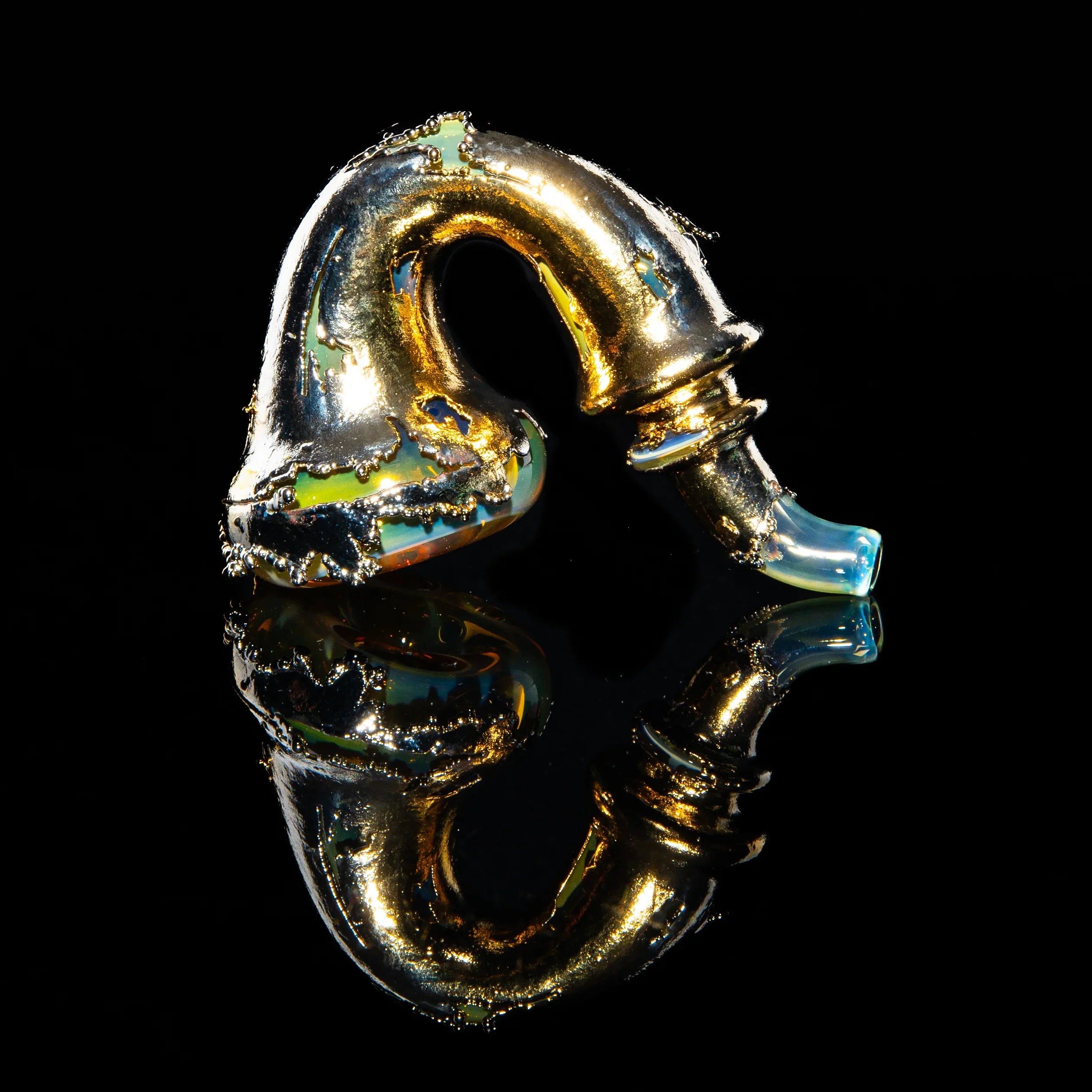 Gold and glass Sherlock pipe with intricate detailing on a black reflective surface