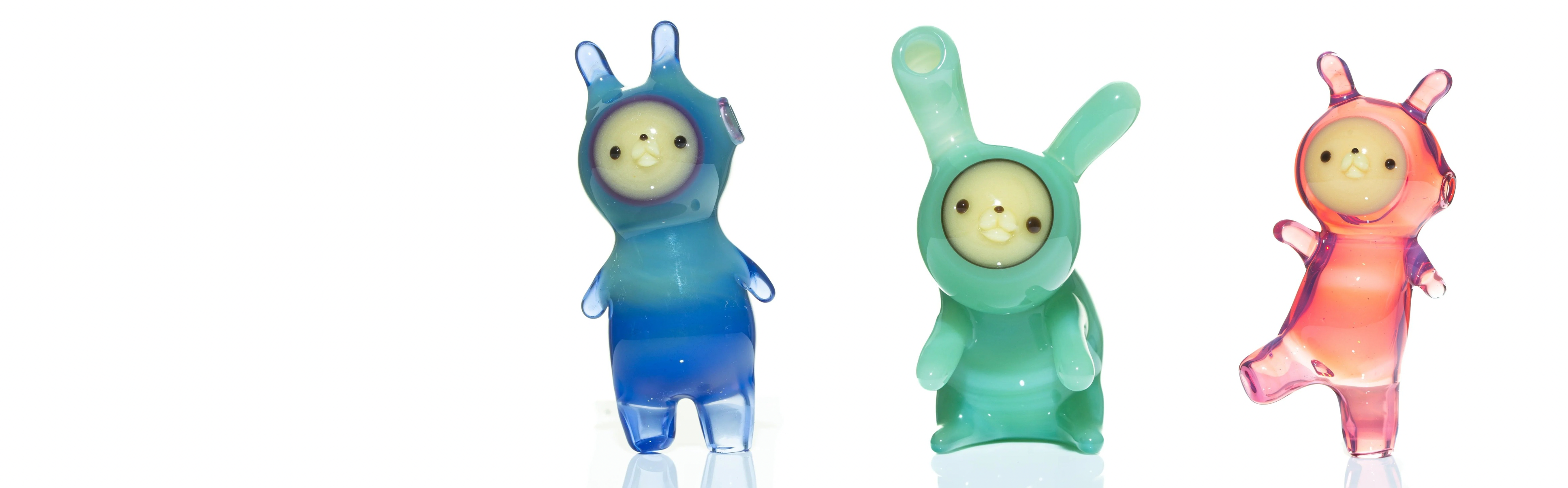 Three colorful glass chappy characters in blue, green, and pink on a white background