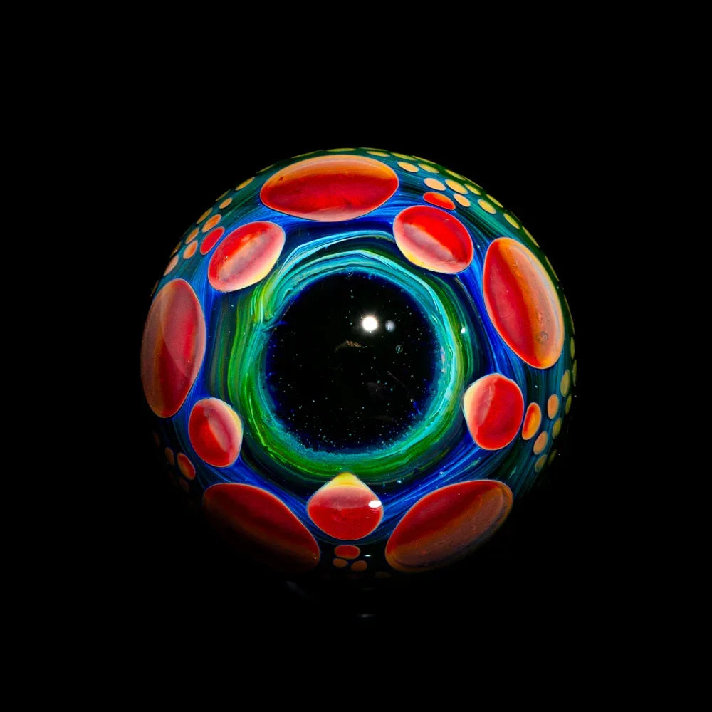 Colorful heady glass marble with blue, green, and red patterns on black background