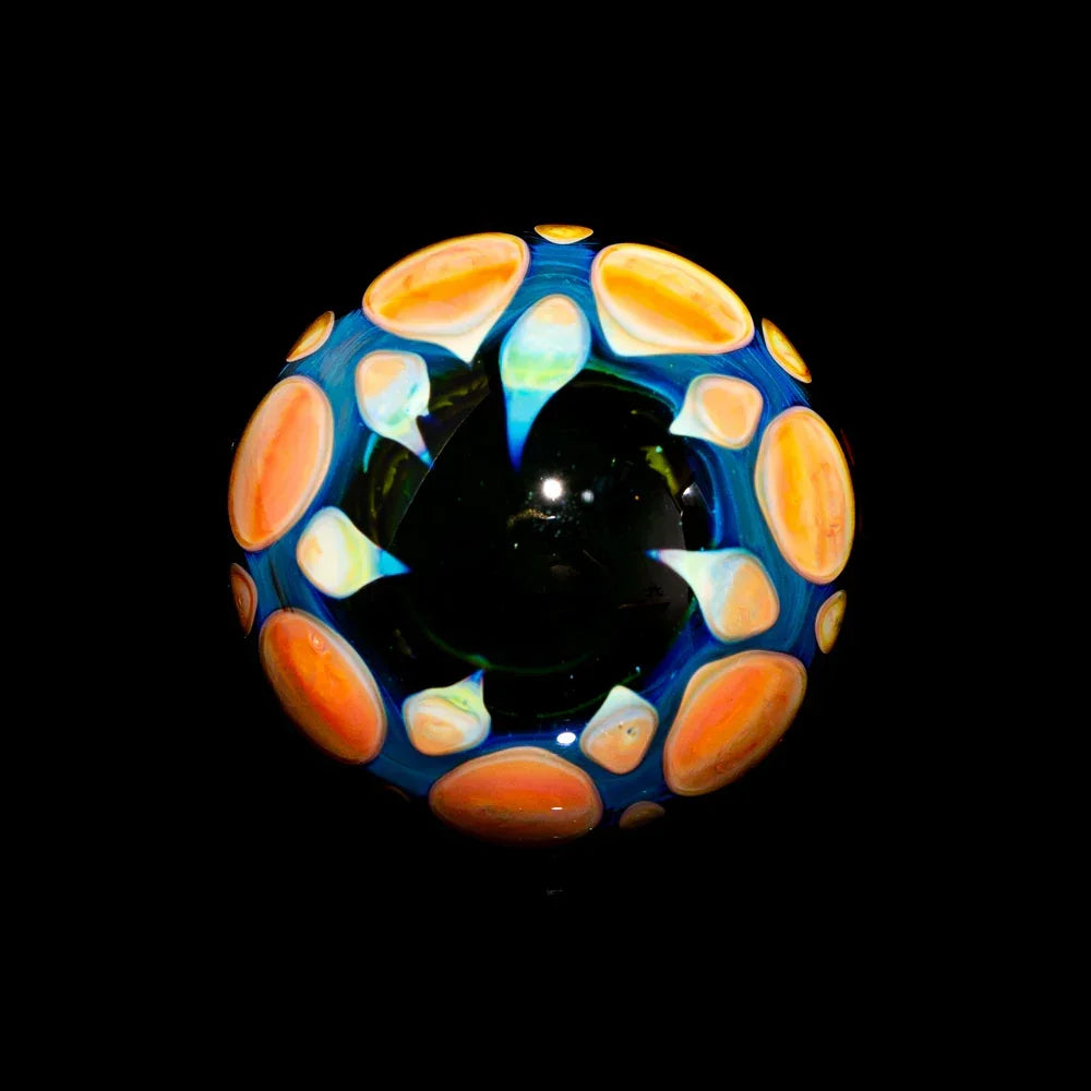 Hand-blown art glass marble with vibrant blue, orange, and yellow patterns on black background