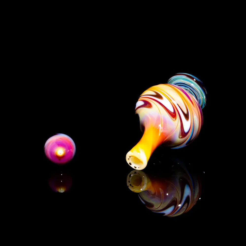 Colorful heady glass carb cap and marble set with swirled patterns on black background
