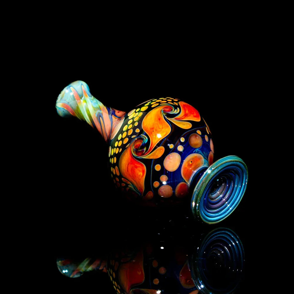 Colorful heady glass pipe with abstract orange and yellow designs on a black background