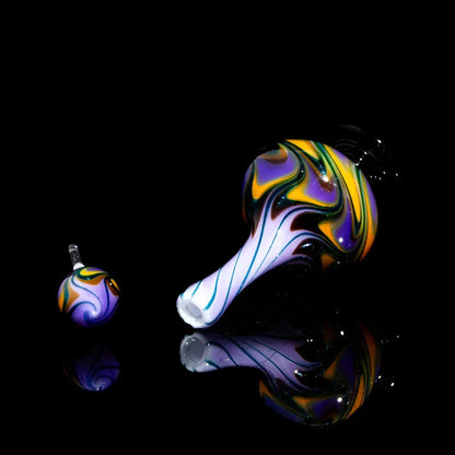Colorful hand-blown glass pipe and carb cap with swirling purple, yellow, black patterns