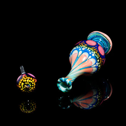 Colorful hand-blown glass pipe with intricate dot and swirl patterns on black background