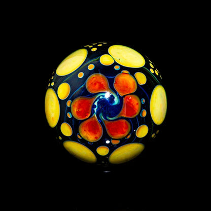 Hand-blown glass marble with red, yellow, and blue psychedelic swirl design on black background.