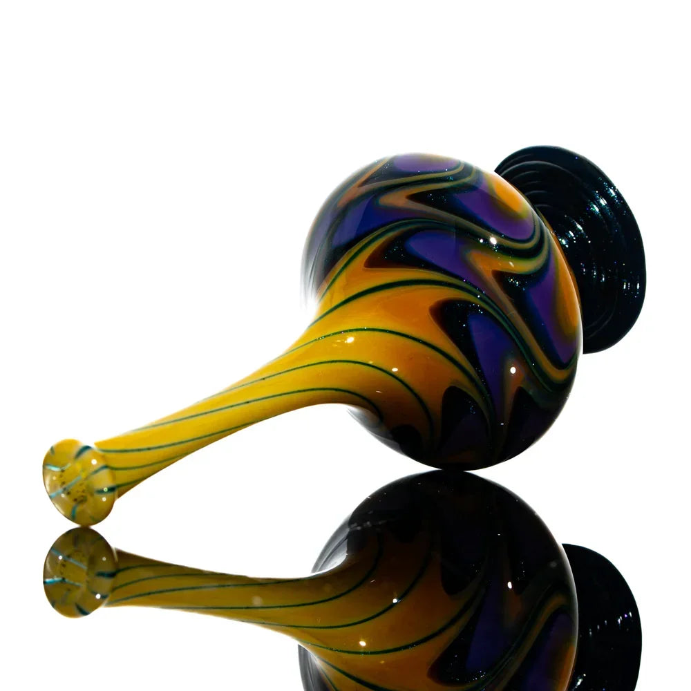 Heady glass carb cap with yellow, purple, and black swirl design on reflective surface