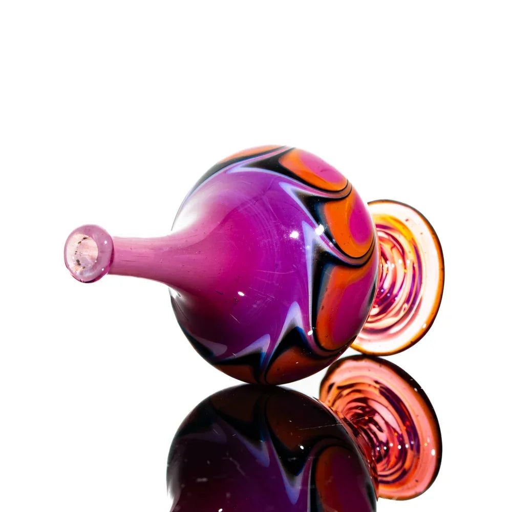 Colorful heady glass pipe with purple, orange, and black swirls on a reflective surface