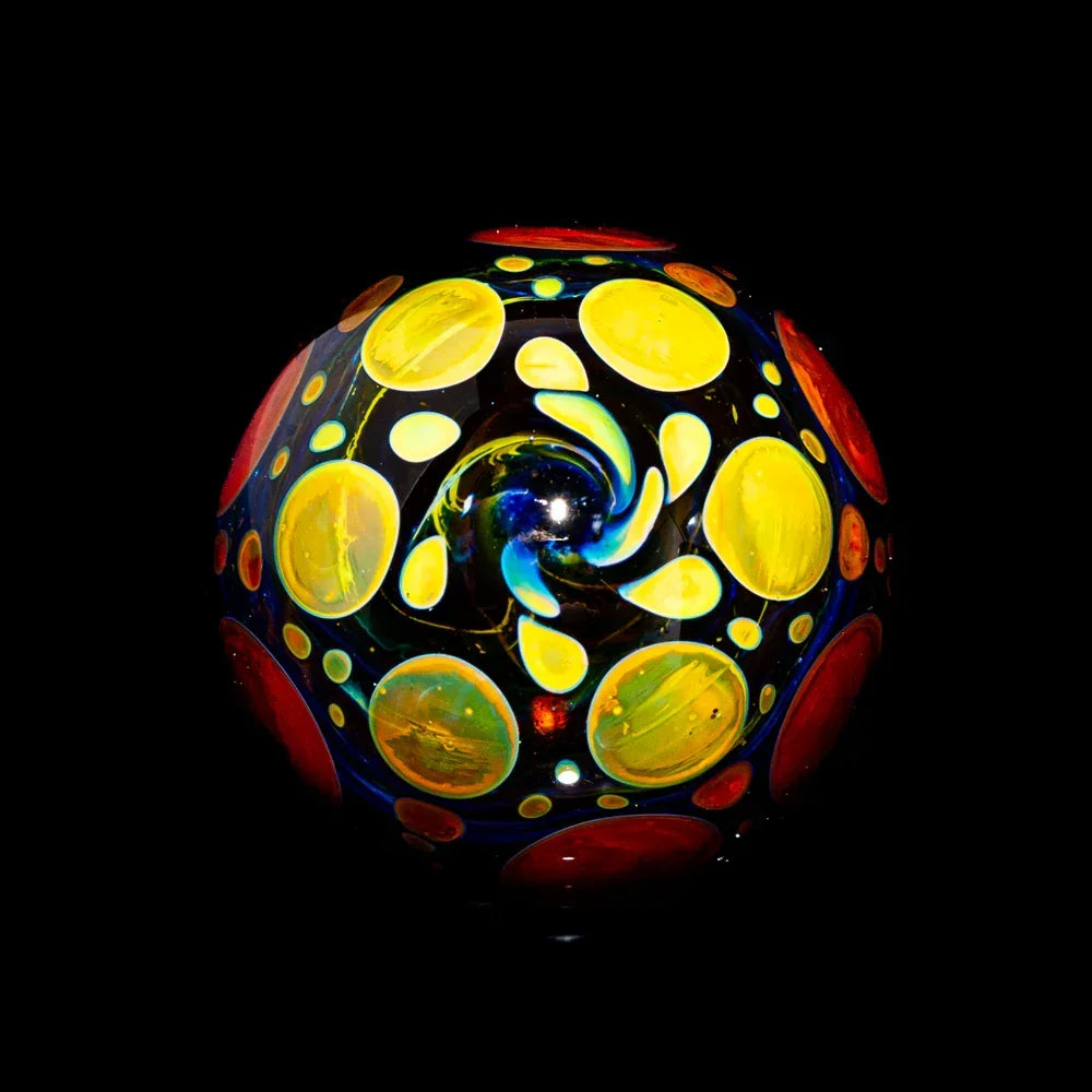 Heady glass marble with vibrant yellow and orange swirl dot patterns on black background