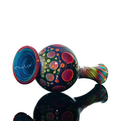 Heady glass perfume jar with colorful dots and swirling patterns on reflective surface