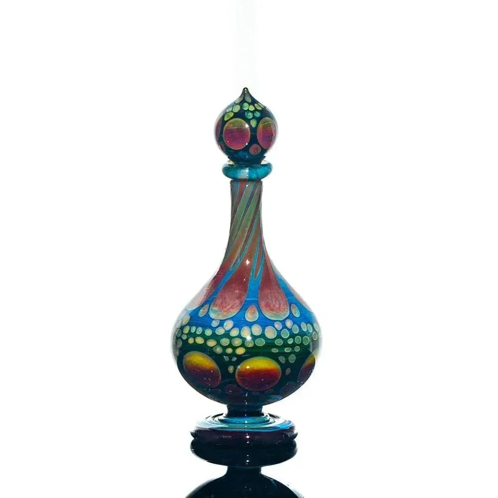 Colorful hand-blown glass perfume jar with intricate dots and swirl designs on clear background.