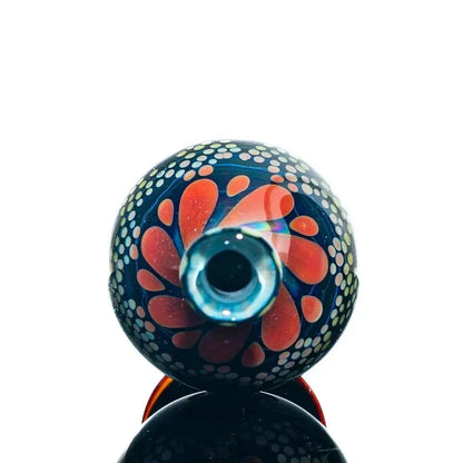 Handcrafted glass jar with blue and orange floral pattern and dotted accents on white background