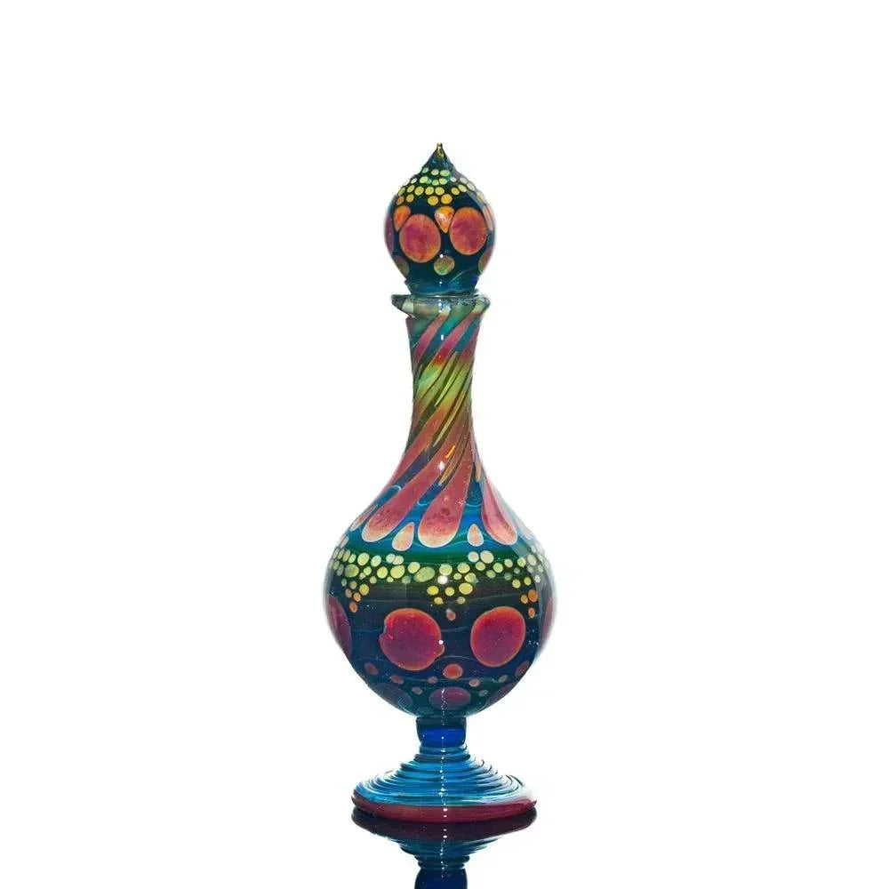 Colorful hand-blown glass perfume jar with abstract dot and swirl pattern on white background