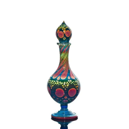 Colorful hand-blown glass perfume jar with abstract dot and swirl pattern on white background