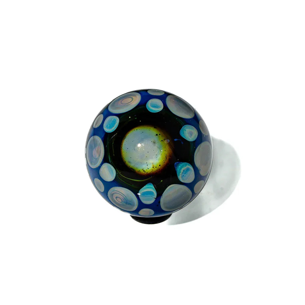 Handcrafted glass marble with cosmic blue and planet-like swirl designs on white background