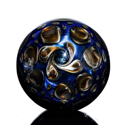 Hand-blown glass marble with deep blue and gold swirling patterns, reflective surface