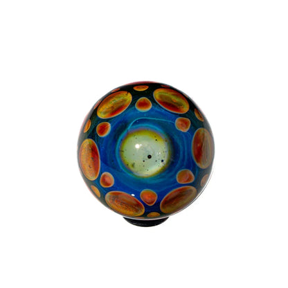 Hand-blown glass marble with blue center and orange sunburst pattern on white background