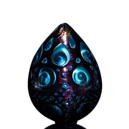 Art glass egg with blue and purple metallic patterns on black background