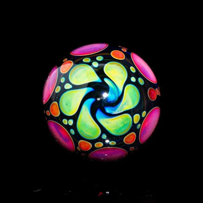 Hand-blown glass marble with vibrant pink, yellow, and green swirl pattern on black background