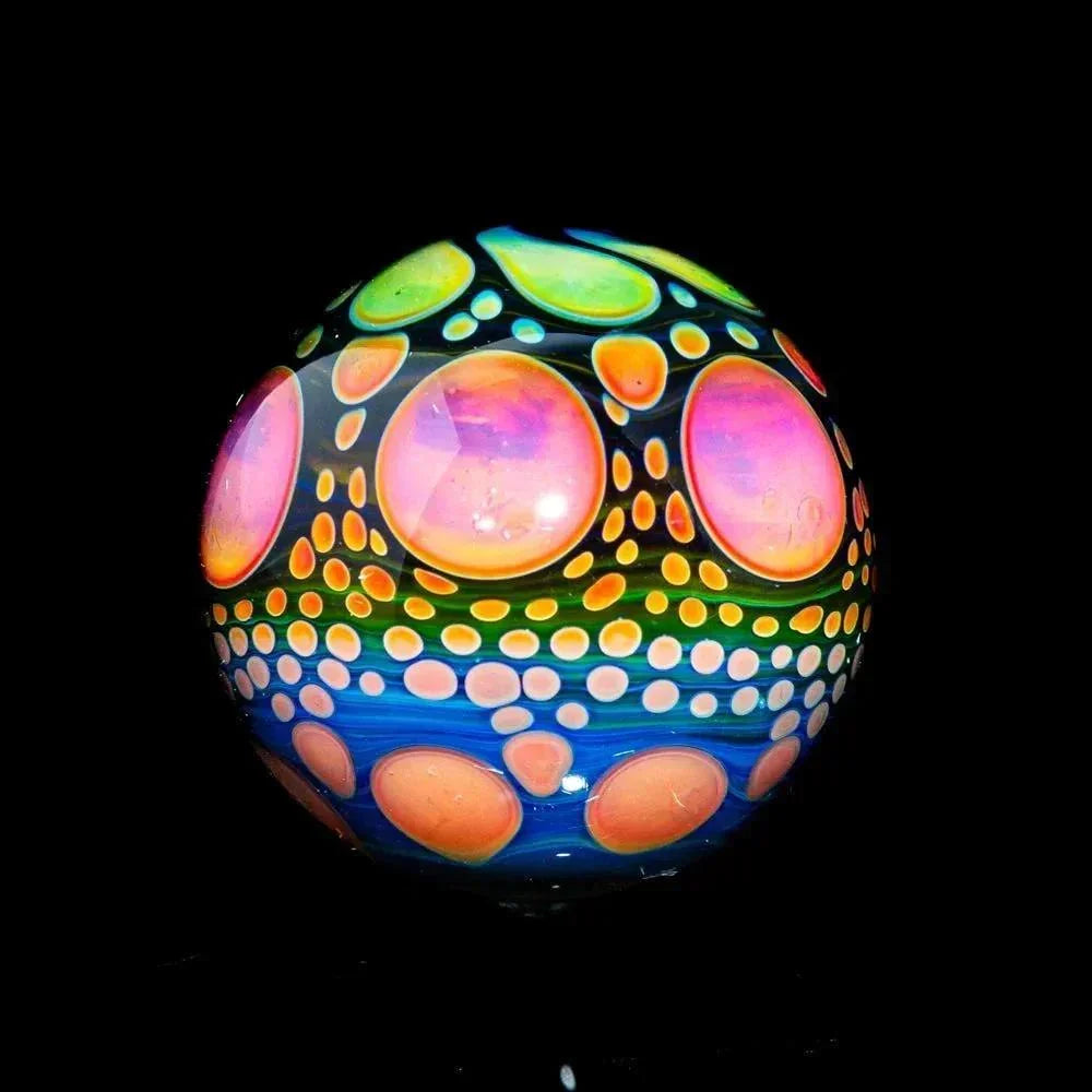 Hand-blown glass marble with colorful pink, orange, and green hobnail pattern on black background.