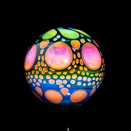 Hand-blown glass marble with colorful pink, orange, and green hobnail pattern on black background.