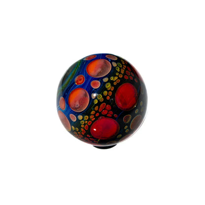 Handcrafted glass marble with vibrant red and orange bubble patterns on a dark background