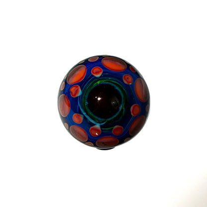 Handmade glass marble with blue base and red polka dots, artistic smoke shop accessory.