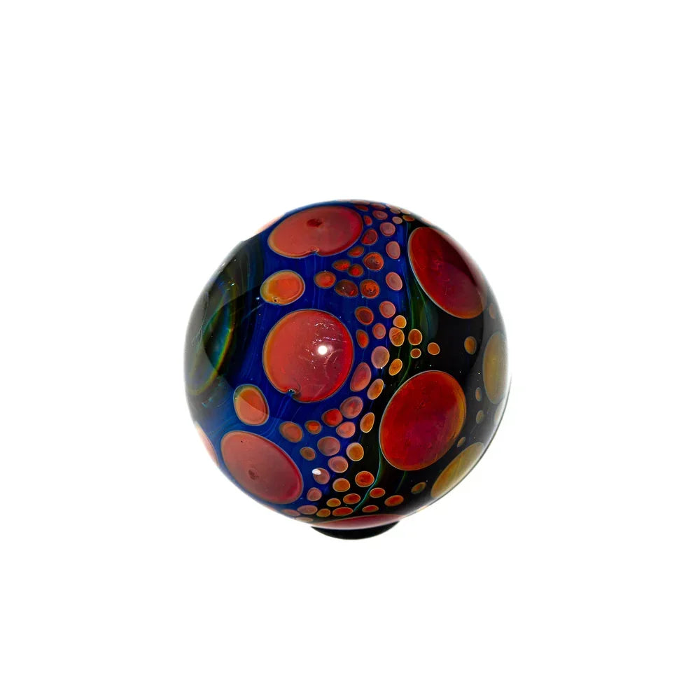 Hand-blown glass marble with colorful red, orange, and yellow bubble patterns on dark background