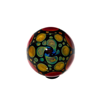 Hand-blown glass marble with colorful yellow and red swirl patterns on black background