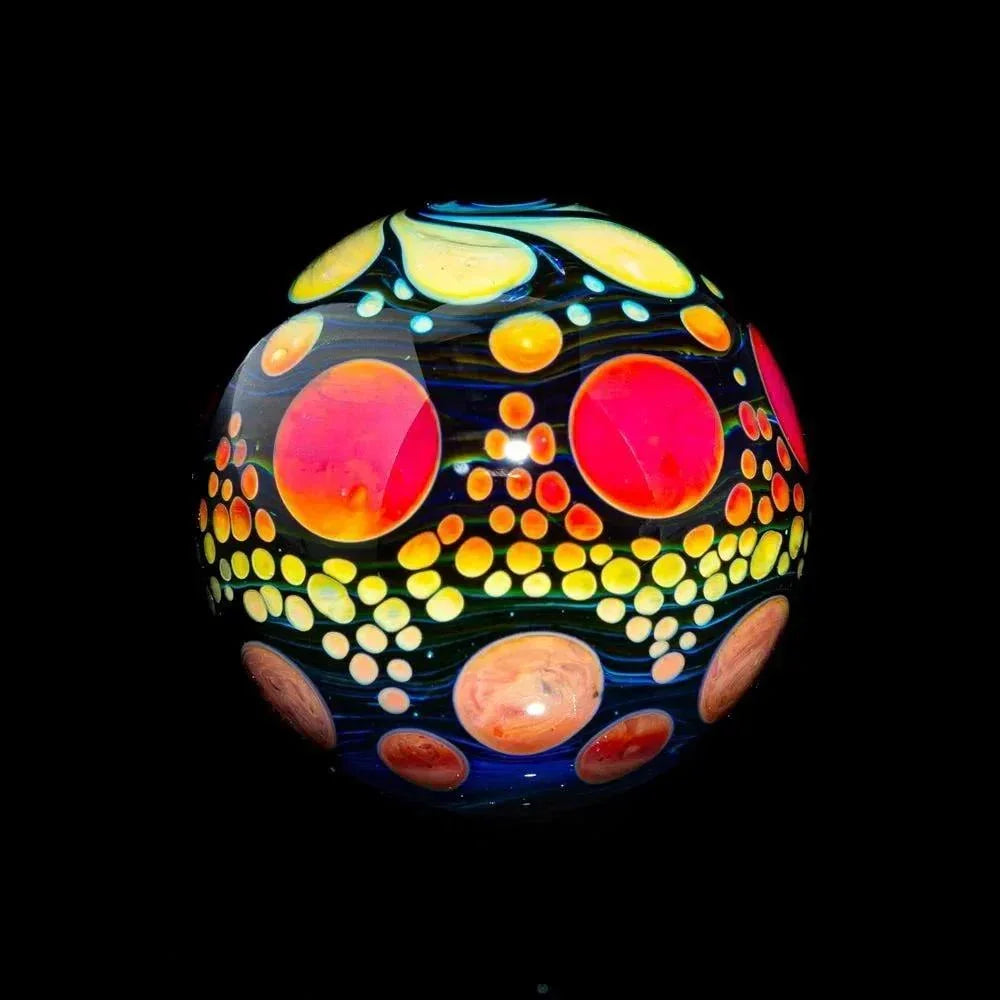 Hand-blown glass marble with vibrant sunset colors and hobnail dot patterns on black background.