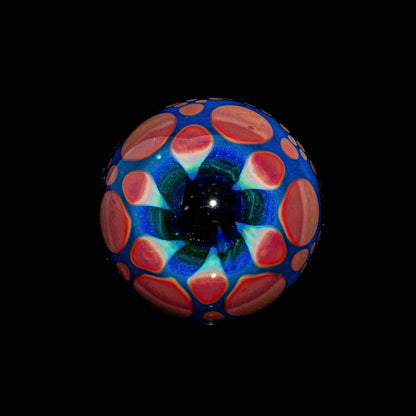 Handblown glass marble with blue, green, and coral hobnail pattern on black background