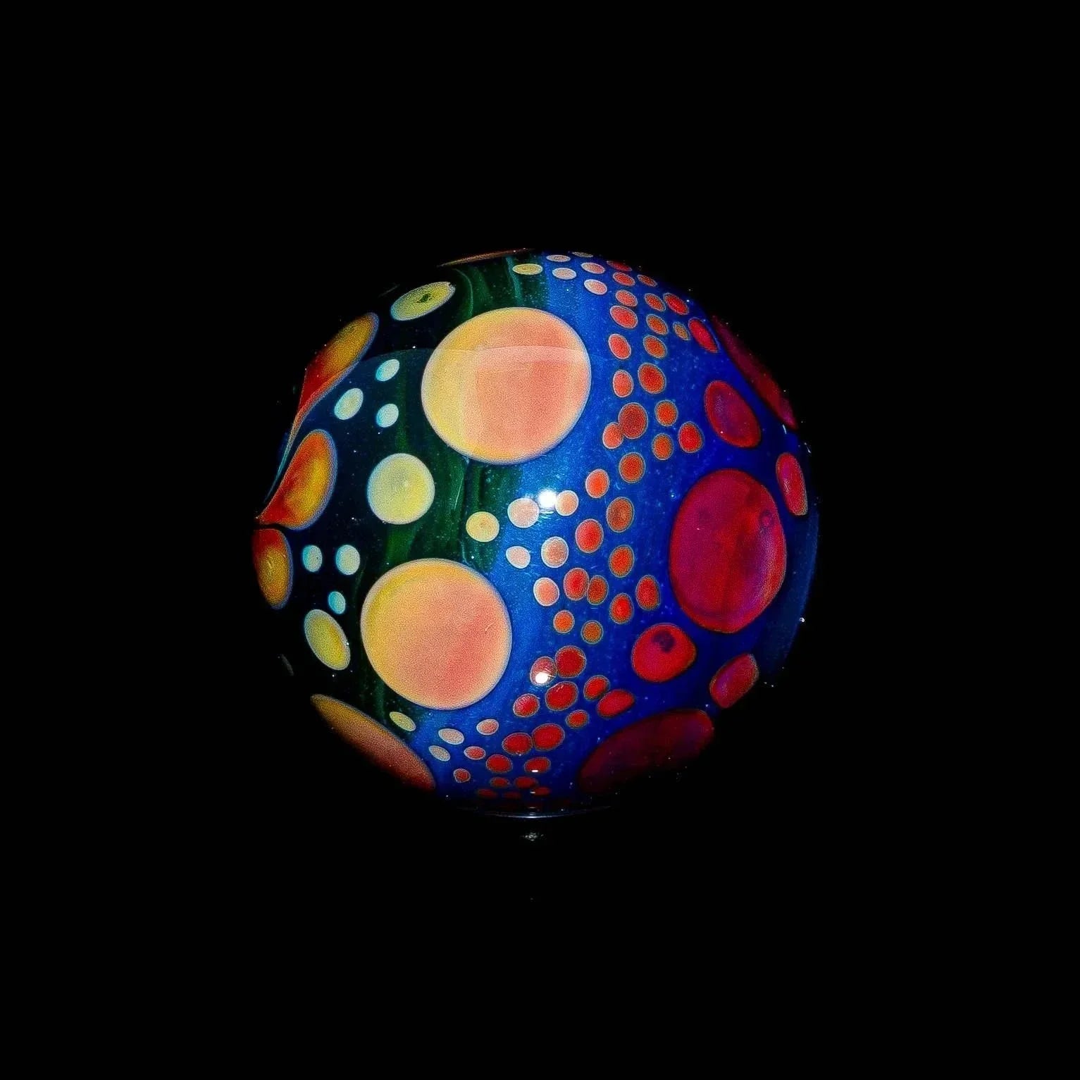 Blue green red hobnail glass marble with colorful bubble dot pattern on black background