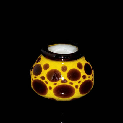 Yellow and brown spotted glass art piece with wide opening on black background