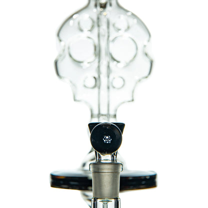 Close-up of intricate clear glass water pipe with unique percolator design, studio background