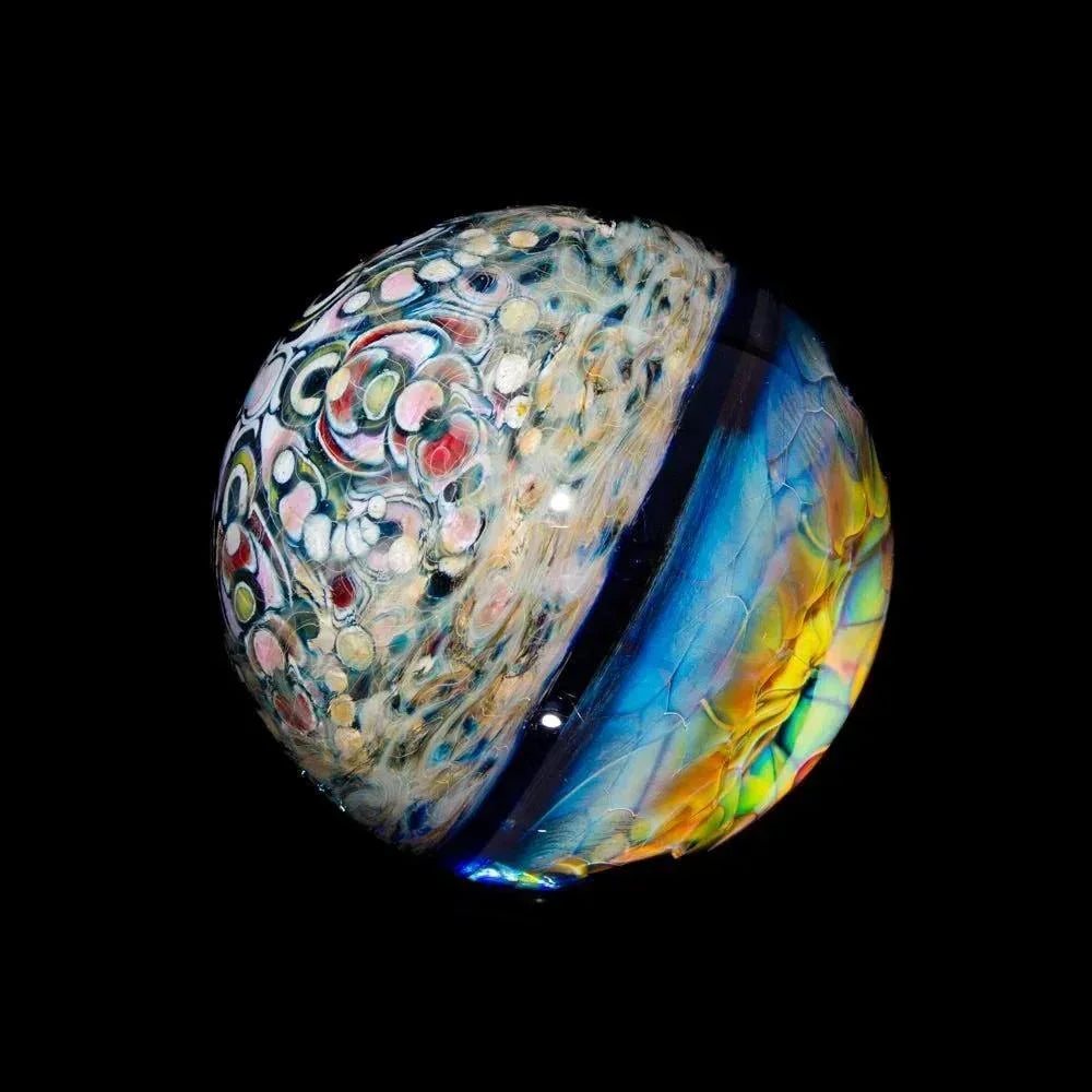 Hand-blown glass marble with intricate multicolor patterns and vibrant details on black background