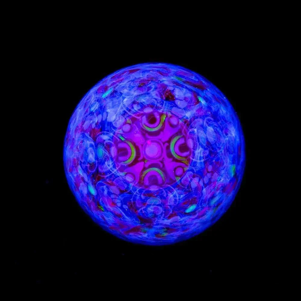 UV reactive glass marble with intricate blue and purple patterns on black background