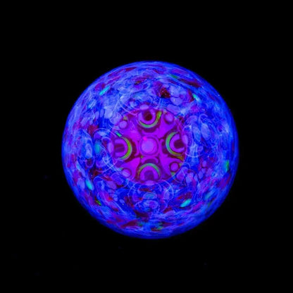 UV reactive glass marble with intricate blue and purple patterns on black background