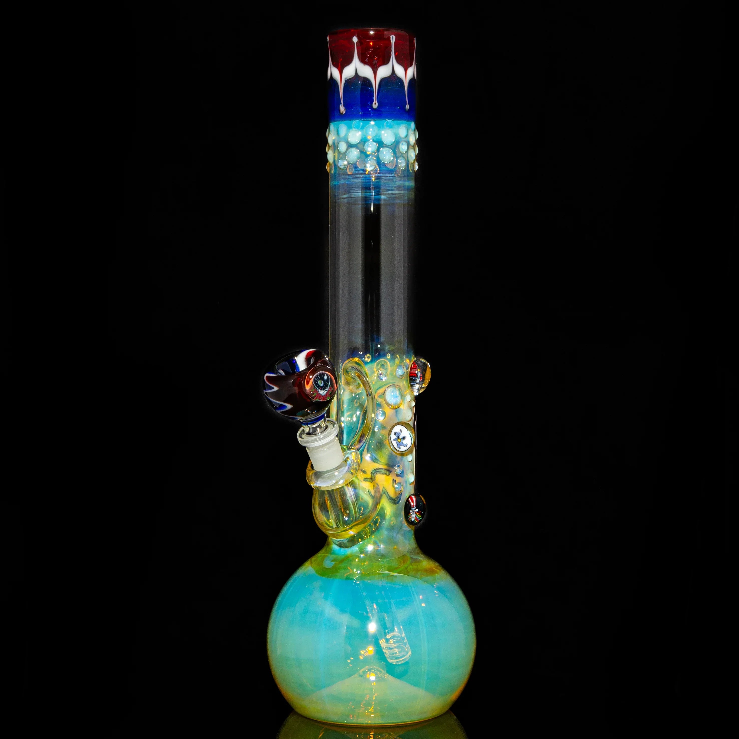Colorful glass water pipe with fumed design, decorative marbles, and patterned bowl on black background.