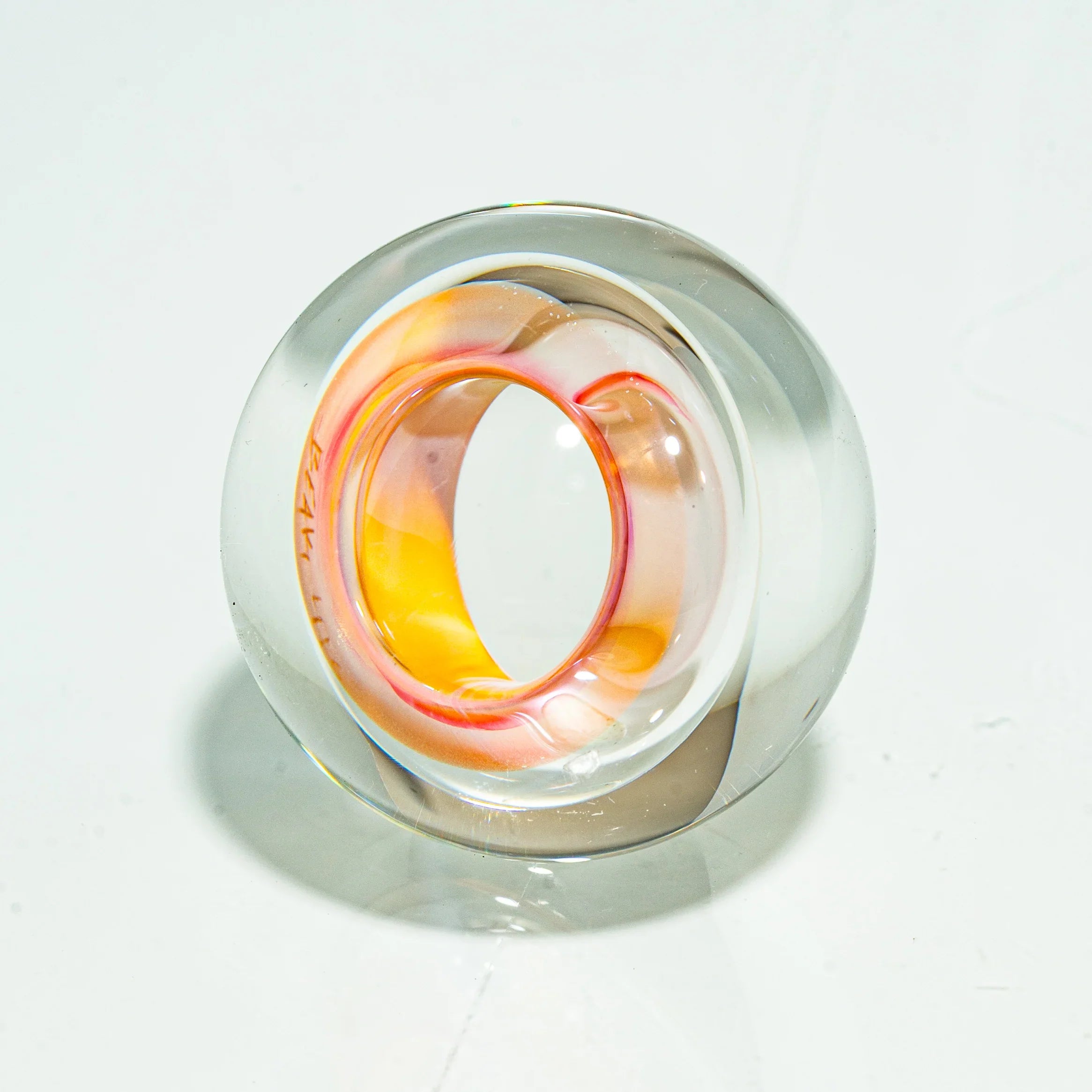 Hand-blown glass carb cap with clear and orange-yellow swirl design on white background